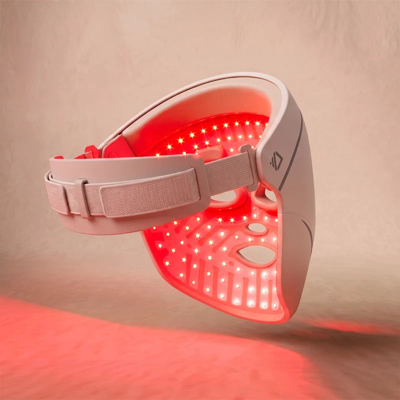 The Dermalux LED Face Mask tilted to show its lit interior, with the head strap and moulded eye guards visible