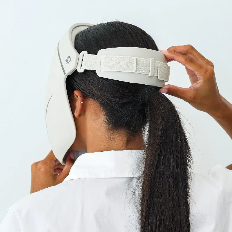 A woman adjusting the elastic head strap of the Dermalux LED Face Mask at the back of her head